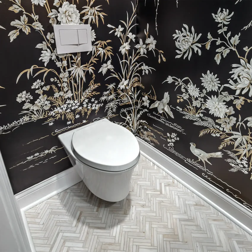 Powder room with black botanical wallpaper and a white toilet