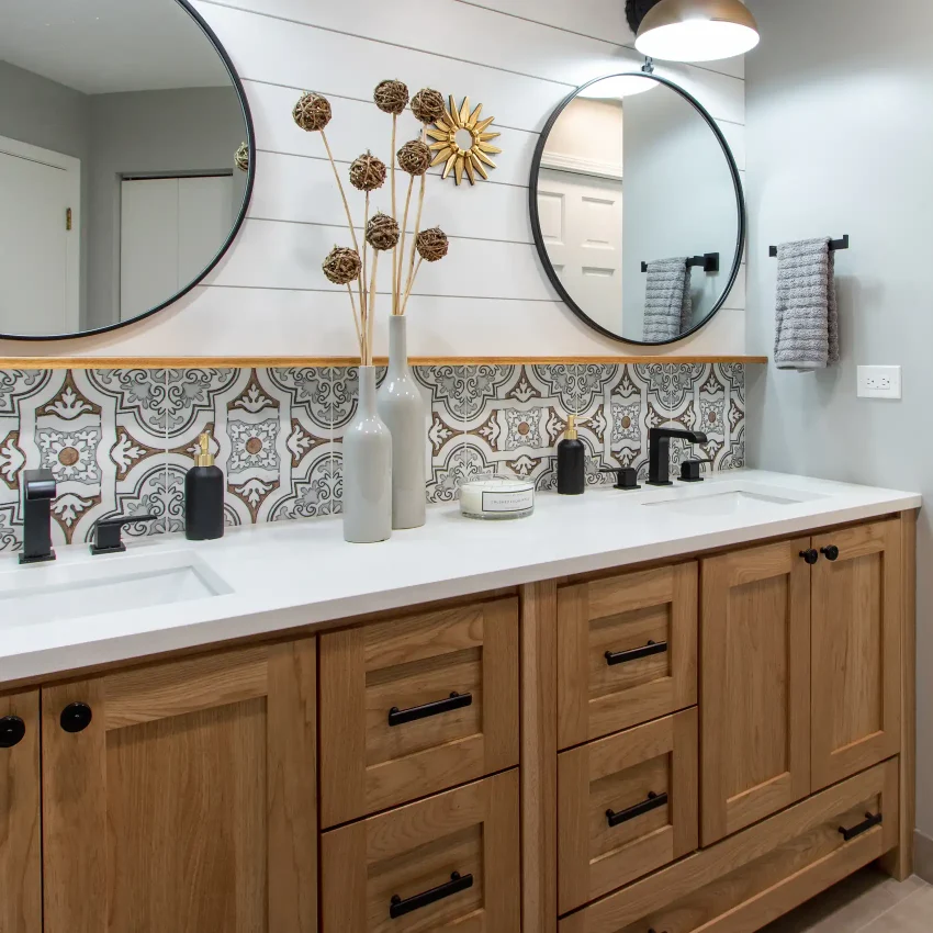 Bathroom with a wood vanity, geometric tile backsplash and circular mirror