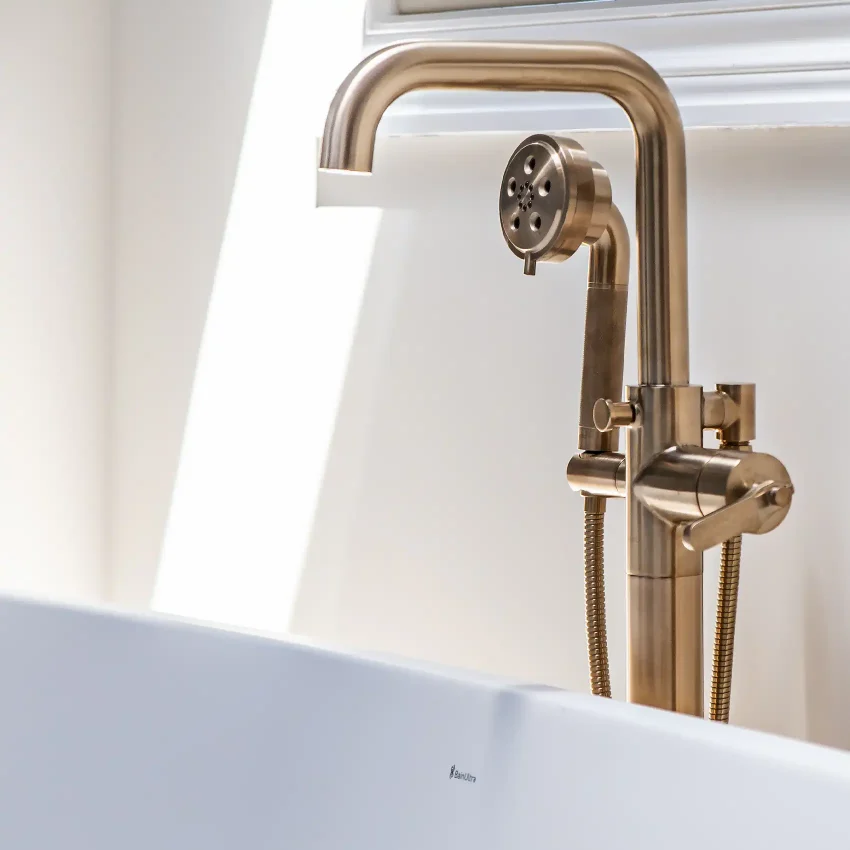 Bathroom with a curved brass tub faucet and white marble counter