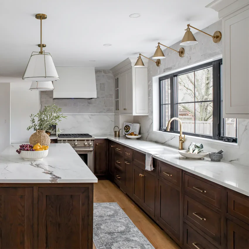 Dark walnut kitchen cabinets with white marble countertops and brass pendants