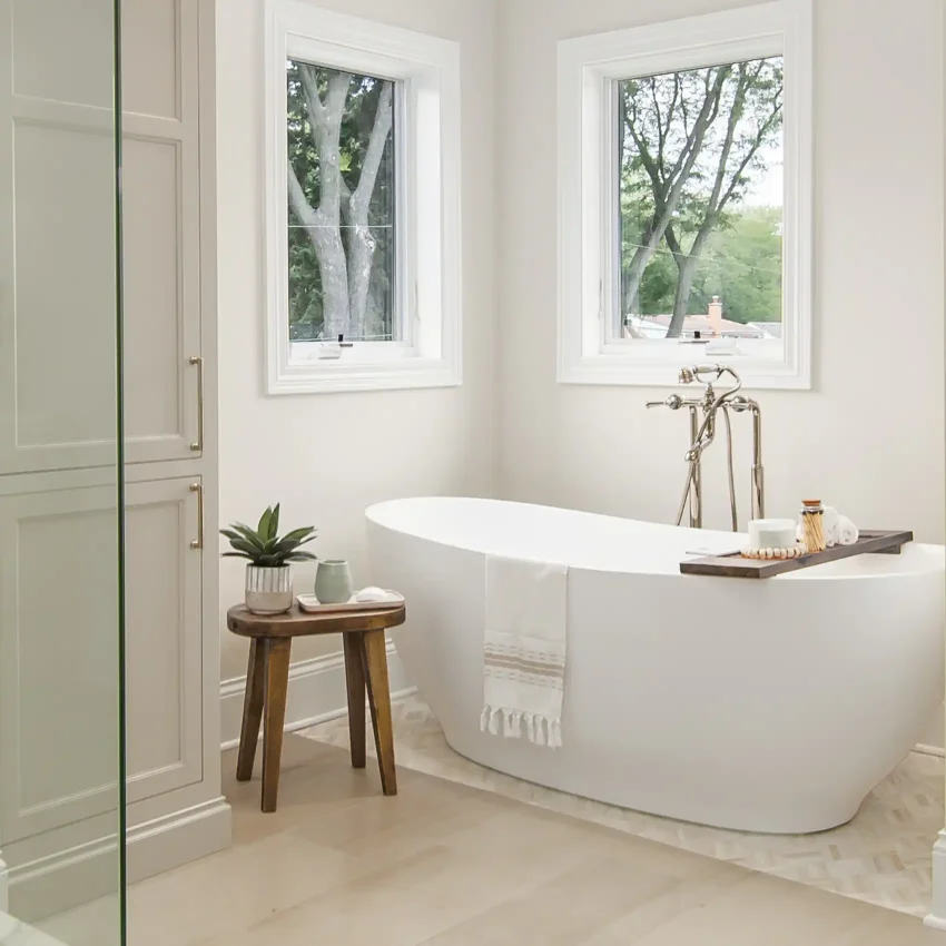 Bathroom with a white freestanding tub, brass floor filler and windows