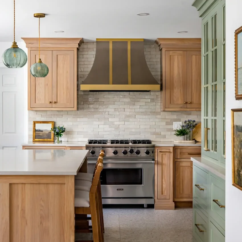 Light oak kitchen cabinets with a brick backsplash and brass pendant