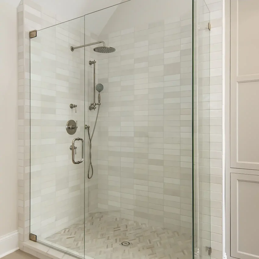 Bathroom with a subway-tile walk-in glass shower and brass fixtures