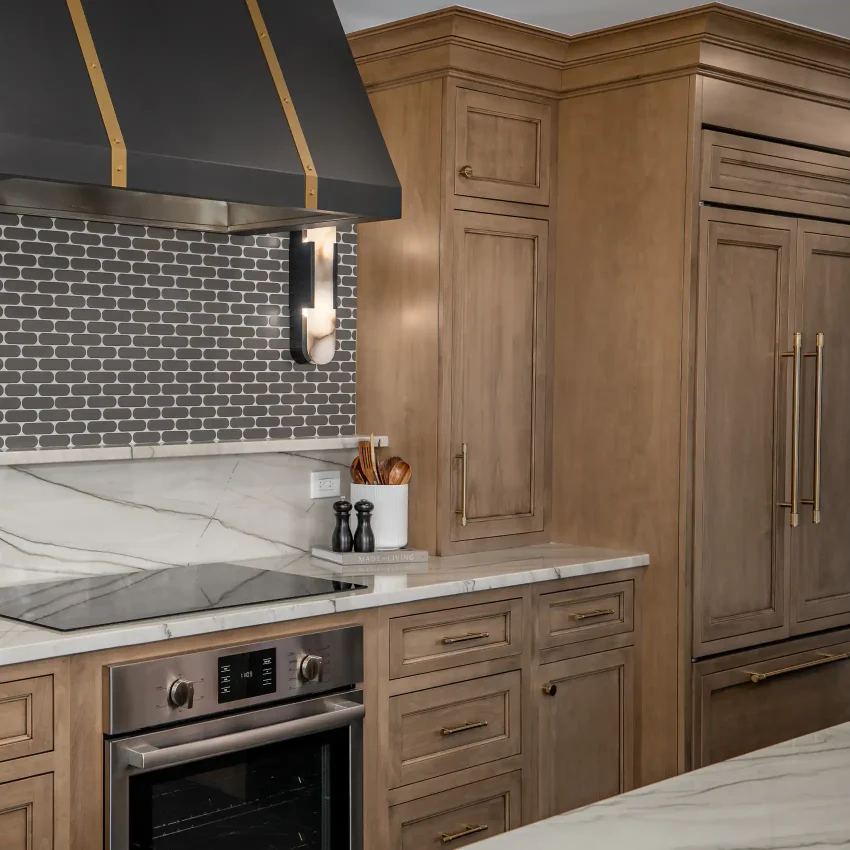 Walnut kitchen cabinets with a dark range hood and brass hardware
