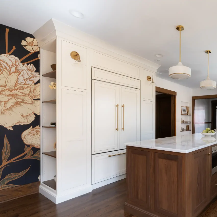 White kitchen cabinets with a walnut island, marble countertops and brass accents